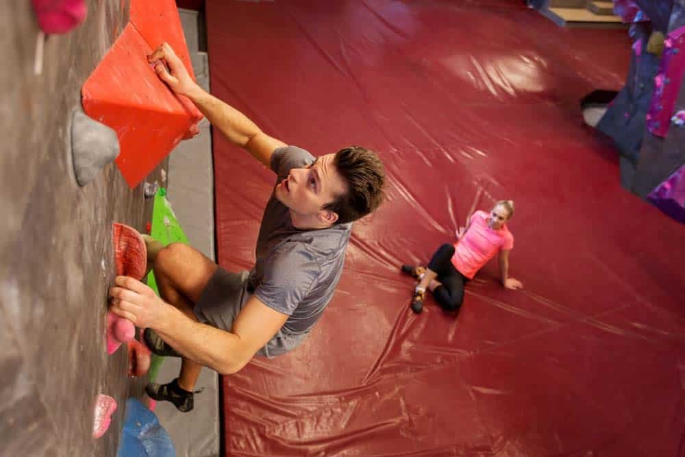 woman watching man indoor climb