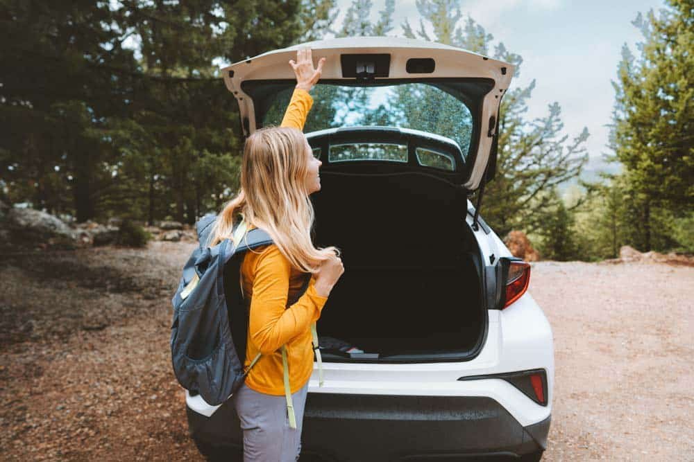 woman closing car boot in nature