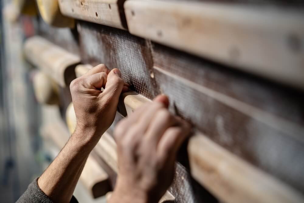 person using crimp grip on a campus board