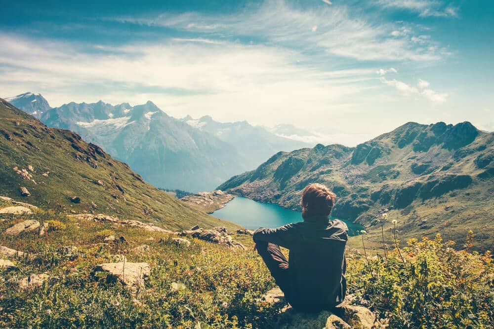 young man being mindful watching lake and mountains