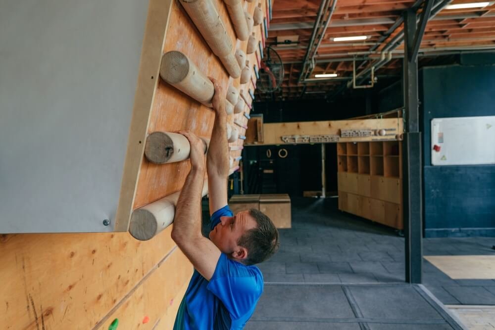 man using sloper campus board