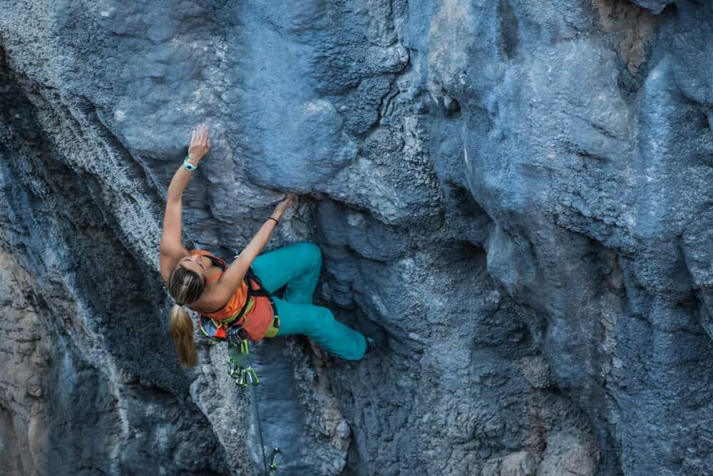 young female climber using kneebar to reach hold