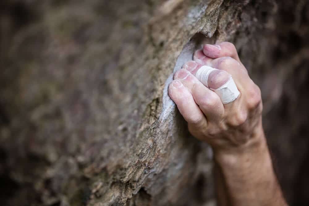 climbers hand crimping hard on rock