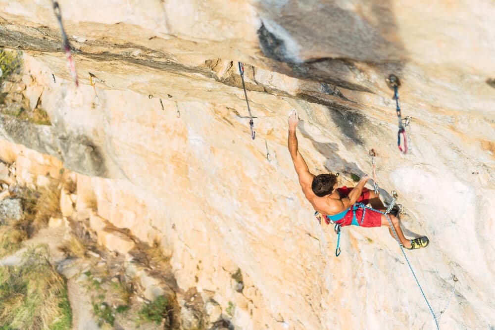 man clipping rope on challenging overhang