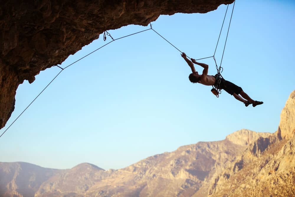 climber being lowered down steep route and collecting quickdraws