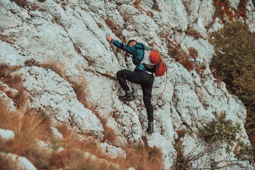 climber scrambling down route with rope on back