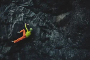 man in fluorescent clothing flagging on dark rock