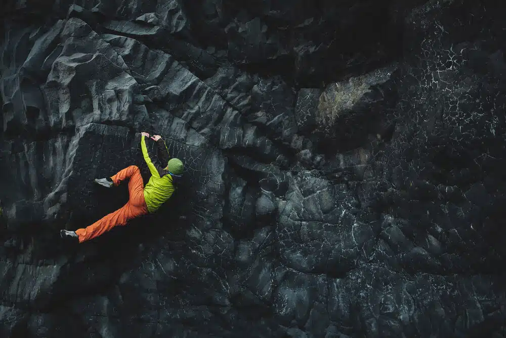 man in fluorescent clothing flagging on dark rock