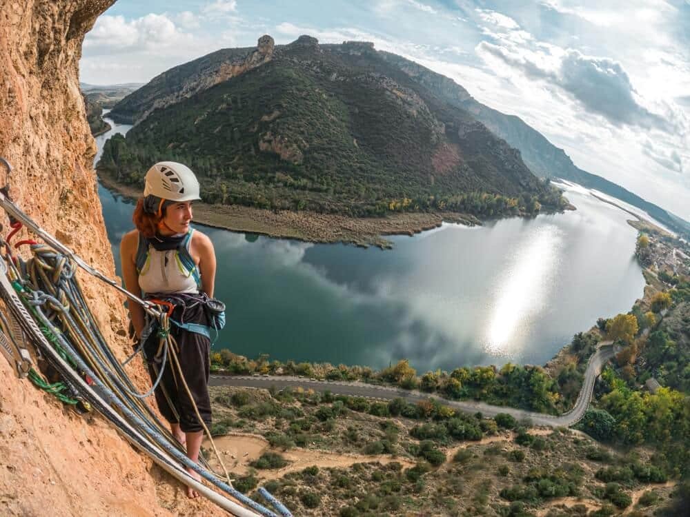 woman at belay station on multipitch with river in background