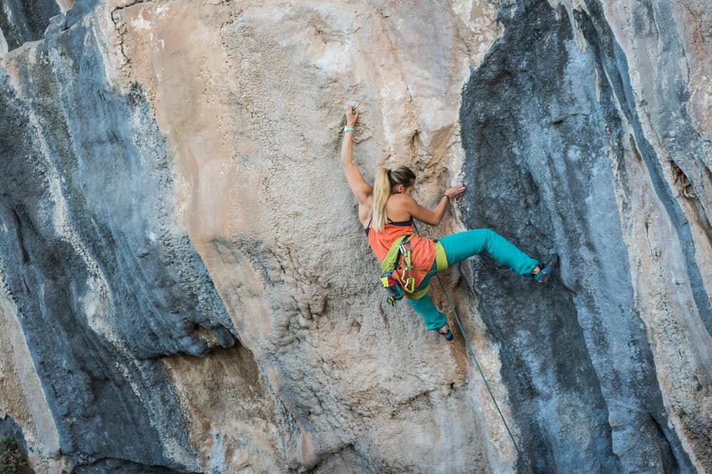 young woman climbing on tufas and pinching hard