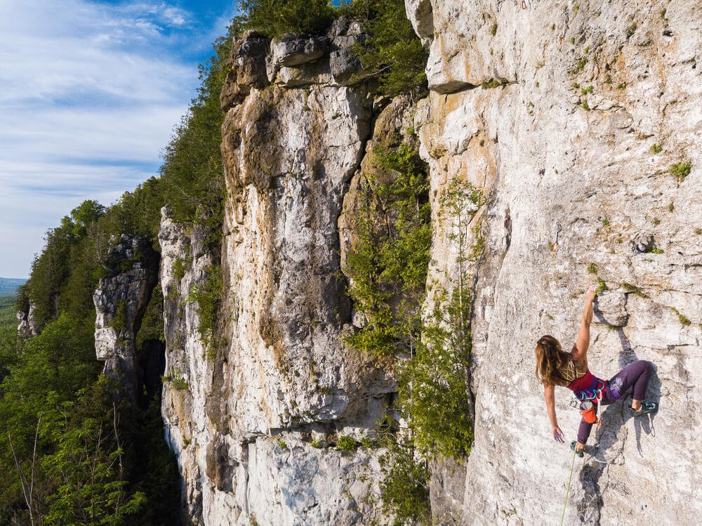 young woman resting on hold on cliff in forest